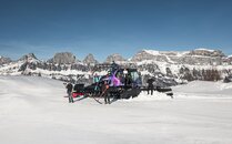 Mitarbeitende in unterschiedlichen Berufen posieren vor einem Pistenfahrzeug im Schnee | © Bergbahnen Flumserberg AG